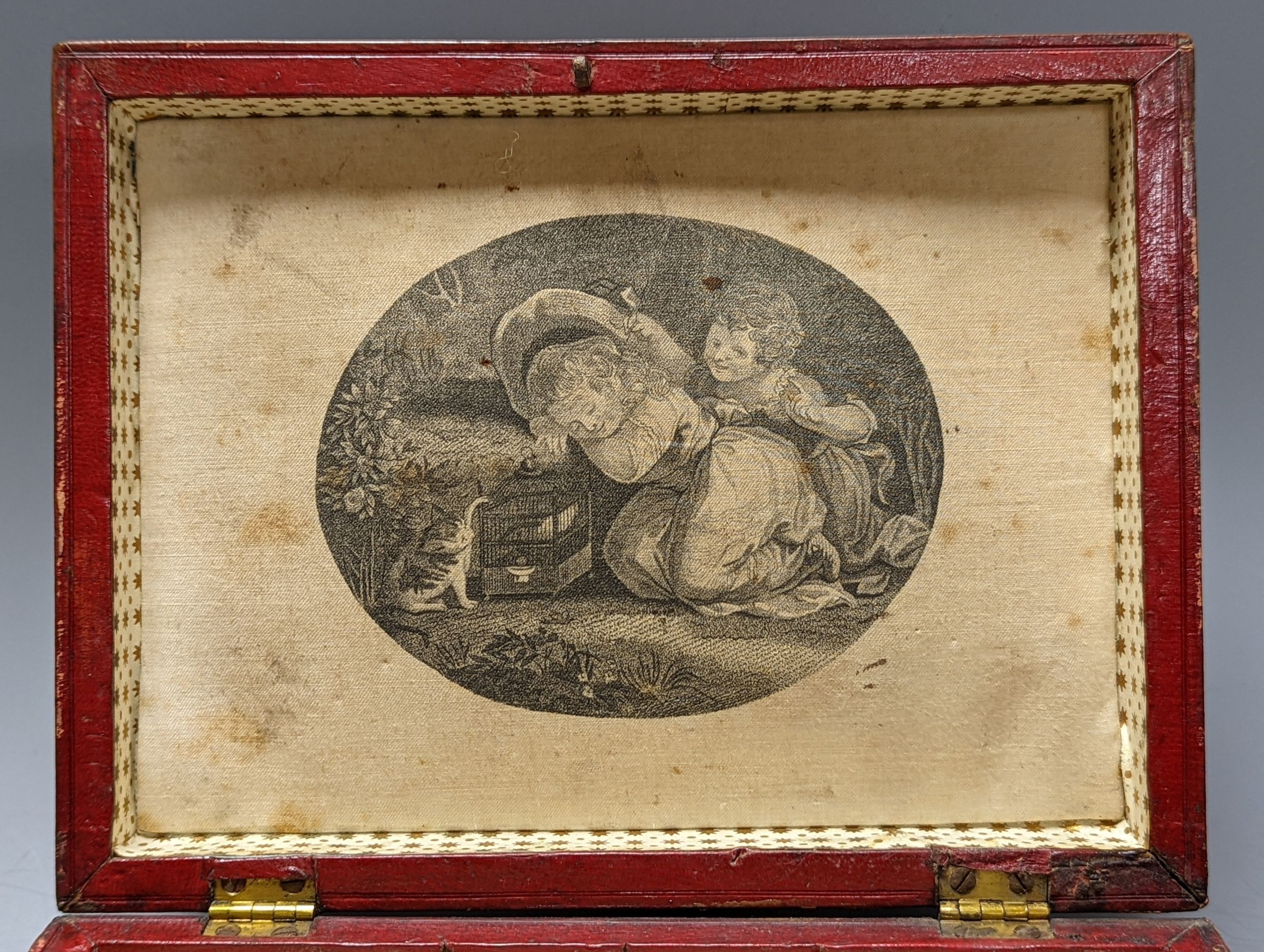 A George IV tooled Morocco leather box, with a silk printed cartouche to interior of the lid, 22 cms wide at base x 12 cms high.